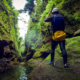 A man stands in a green moss covered canyon taking a photo in Dominica