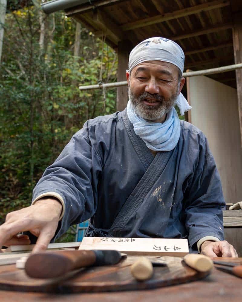 Traditional knifemaking in Kochi Japan, the blacksmith sits at a table with the knives