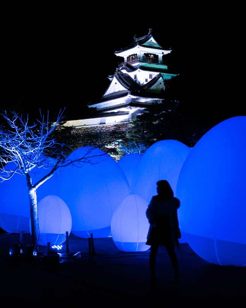 A person illuminated by the floating balls of the teamLab installation