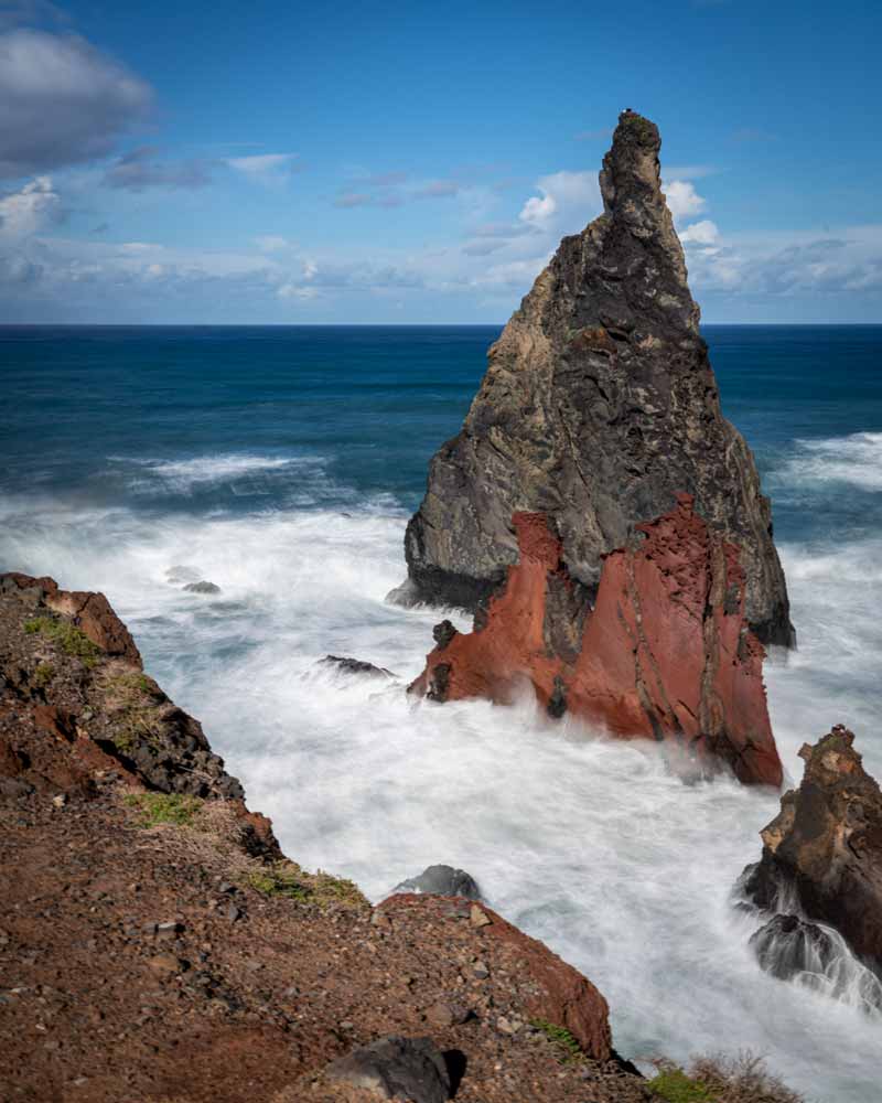 Waves crash against rocks in a long exposure photo, showing the water whisping around the rocks