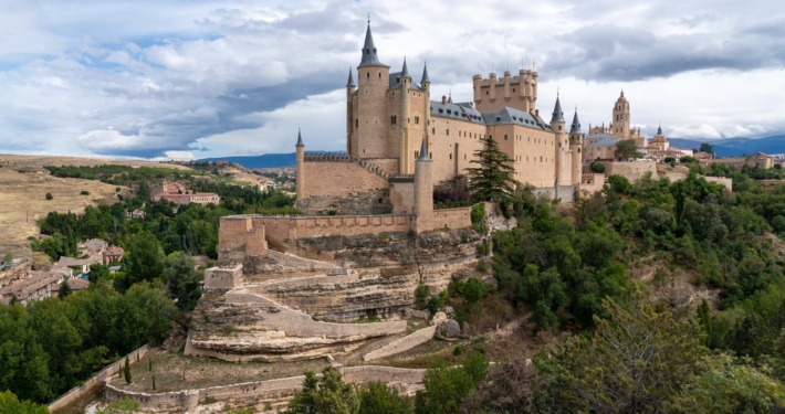 The Alcazar of Segovia on a cloudy day perches on a hill