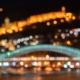 A blurry shot of Tbilisi at night, with the light and shape of the fortress and river bridge